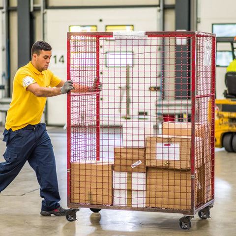 Male worker pushing a wheeled cart with packages, showcasing Four 4 Inch Antique Bronze Swivel Casters With Locking Brake For Heavy Duty Tables Chair Legs Providing Silky Smooth Glide And Kickass Stability On Hard Floors.