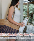 Woman holding Portable Stainless Steel Vacuum Insulated Breastmilk Cooler Bottle while carrying a large straw bag.
