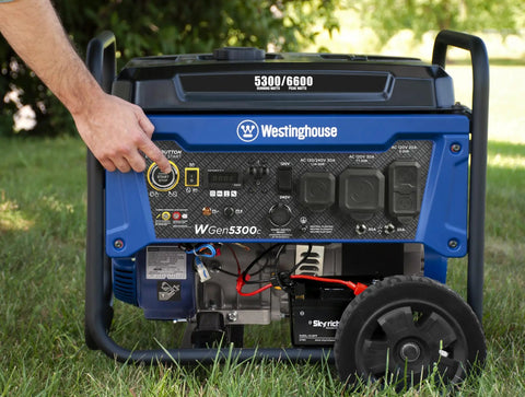 Close-up of Beast 6600 Watt Portable Generator For Home Backup With Remote Start and CO Sensor outdoors on grass, hand on button.