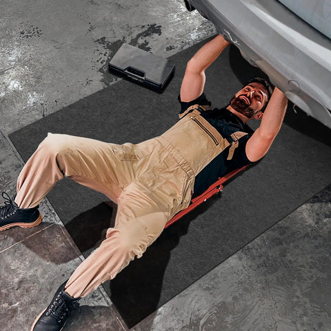 Mechanic working under car on 4 Pack 36 By 72 Inch Oil Spill Mats For Under Car And Garage Drips Absorbent Pads With Rubber Backing