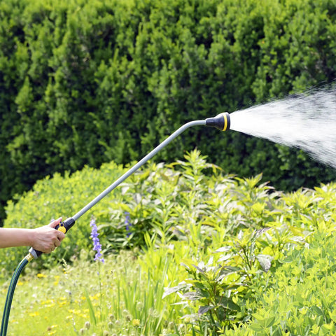 Gardener using RelaxGrip 33 Inch Shower Head Watering Wand With Quick Connects And GentleRain Shower Head For Easy Thumb Control Ideal For New Plantings And Delicate Flowers Durable Garden Hose Wand For Hassle Free Watering amid lush greenery
