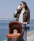 Mother with stroller by water using 2 In 1 Cup Holder Attachment For Q1 Wagon Only, With Secure Grip And Easy Access, in black.