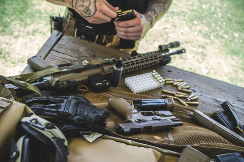 M-Pact 0.5mm High-Dexterity Covert Tactical Work Gloves With Touchscreen Capability on table with firearms and ammunition