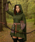 Action shot of a woman in a green hooded outfit holding a bow, featuring steampunk elements for cosplay.