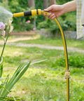 Person using a garden hose with Garden Hose Repair Connector Kit With Clamps For Three Quarter Or Five Eighth Inch Aluminum Hoses Includes Four Sets Of Male And Female Fittings And Washers Durable Aluminum Connectors With Stainless Steel Clamps to water plants.