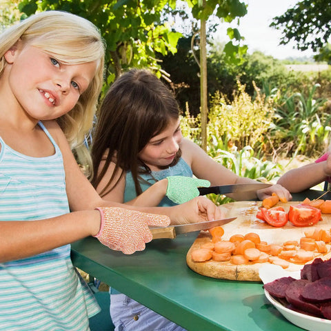 Kids wearing Kids Cut Resistant Gloves Level 5 Four Pairs Pack In Bright Colors while preparing vegetables outdoors.