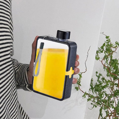 Person holding Flat Square Water Bottle For On The Go Hydration, Leak Proof And Drop Proof, black exterior with yellow liquid inside.