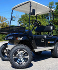 Black golf cart with oversized tires and canopy on paved road