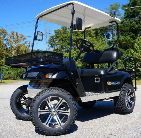 Black golf cart with oversized tires and canopy on paved road