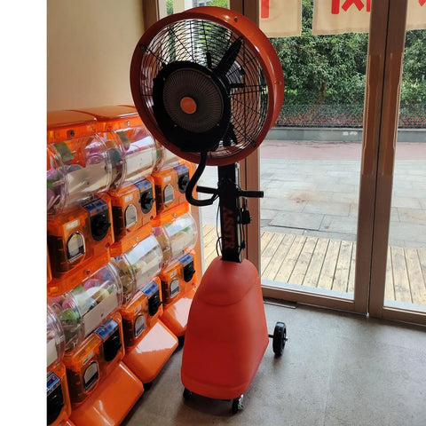 No Sweat Commercial Misting Fan Delivers Beast Mode High Velocity Airflow For Restaurants And Warehouses Featuring Rock Solid Metal Housing And Quick Adjustable Tilt Swivel In Blue, standing near a large window.