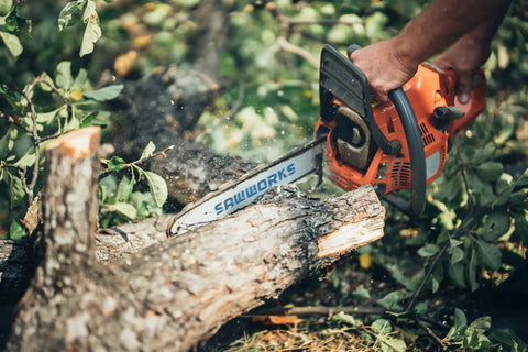 Person using a chainsaw to cut a log in a forest setting, showcasing power and efficiency for timber work.