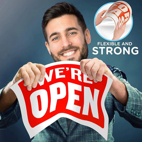 Man holding a red 'We're Open' sign showcasing its flexibility and strength, indicating the material's durability.