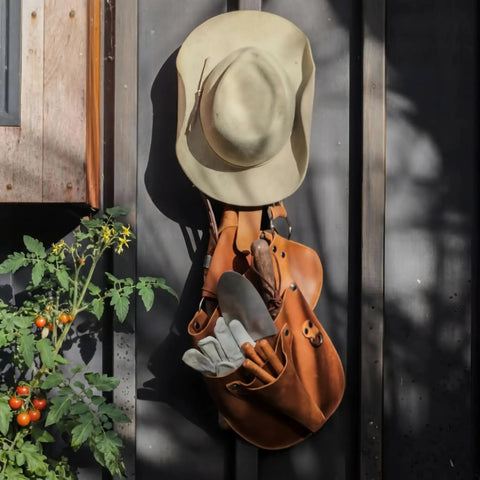 Durable Leather Garden Tool Belt For Women hanging with gloves and tools, light brown leather, outdoor use