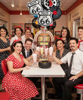 Group enjoying milkshakes in a 50s diner with Route 66 Retro Party Balloons Kit With Vintage Car Tire Decor And Vinyl Record Foil Balloons.