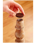 Hand applying brown felt pad from Felt Furniture Pads Pack 162 Pieces Round Brown Self Stick Protect Hardwood Floors to chair leg.