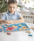Child playing with World Map Wooden Puzzle For Kids Ages 4 To 6: Learn Continents And Oceans With Landmarks, Animals And Marine Life.