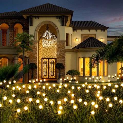 Four Pack Solar Garden Path Lights With 8 LED Firefly Glow Waterproof Outdoor Yard Decor illuminating a lush garden at dusk