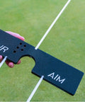 Hand holding part of All In One Golf Training Tool With 11 In 1 Alignment Sticks And Swing Plane System for aim and alignment on grass