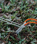Ultralight Titanium Tent Pegs 165mm V-Shaped Stakes For Soft Ground Camping Gear in grass with orange cord