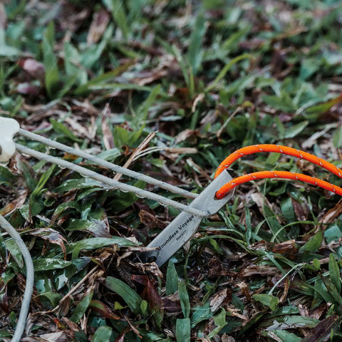 Ultralight Titanium Tent Pegs 165mm V-Shaped Stakes For Soft Ground Camping Gear in grass with orange cord