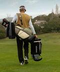 Golfer carrying clubs and Approach R50 Golf Launch Monitor And Simulator Bundle With Three Camera Precision Built In Ten Inch Color Touchscreen Carrying Case Advanced Ball And Club Metrics Real Time Data And Swing Coach Insights on course