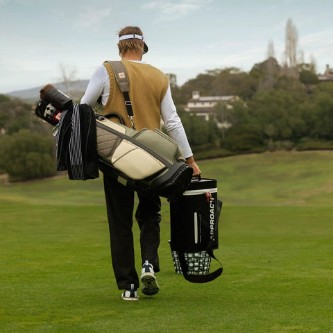 Golfer carrying clubs and Approach R50 Golf Launch Monitor And Simulator Bundle With Three Camera Precision Built In Ten Inch Color Touchscreen Carrying Case Advanced Ball And Club Metrics Real Time Data And Swing Coach Insights on course