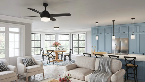 Modern kitchen and dining area with beige sofa, light fixtures, black chairs, and blue cabinets