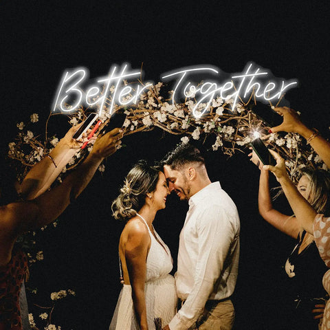 Couple under Better Together Neon Sign With Remote, Large Two Part Wedding Decor Kit, surrounded by guests taking photos
