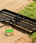 Heavy Duty Lawn Leveling Rake With 78 Inch Long Handle 36 By 12 Inch Head on sand and grass.