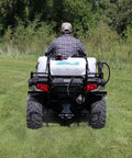 Person operating ATV with Beefy 15 Gallon ATV Broadcast Sprayer With 7 Ft Swath, 2.2 GPM Pump, 70 PSI Max on grassy field