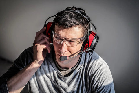 Man using Wireless Electronic Hearing Protector With Bluetooth Technology And External Noise Canceling Boom Mic For Clear Team Communication In Noisy Environments NRR 26 dB Premium Gel Cushions Push To Talk App For Fast Group Chat in a work setting