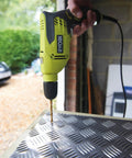 Compact Hammer Drill With Variable Speed Trigger And Reversal Built used on metal surface, showing quick release chuck and drill bit.