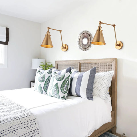 Gold Brass Industrial Swing Arm LED Wall Sconce with Adjustable Metal Shade over a bedroom bed in farmhouse style setting.