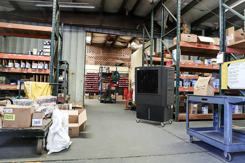 Industrial Swamp Cooler With 22000 CFM And 46 Gallon Water Tank in a warehouse setting, providing cool airflow among shelves.