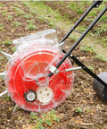 Corn And Soybean Seeder For Backyard Garden With 12 Seed Holes Hand-Push Roller Planter in a garden setting