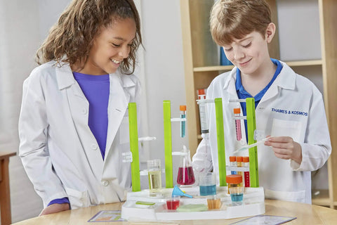 Children using Ooze Labs Chemistry Station Science Kit For Kids With 57 Pieces And 20 Safe Experiments including test tubes and beakers.