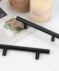 Flat Black 3 Inch Center To Center Bar Cabinet Pulls 5 Pack displayed on table with magazine and candle, modern T-bar handles