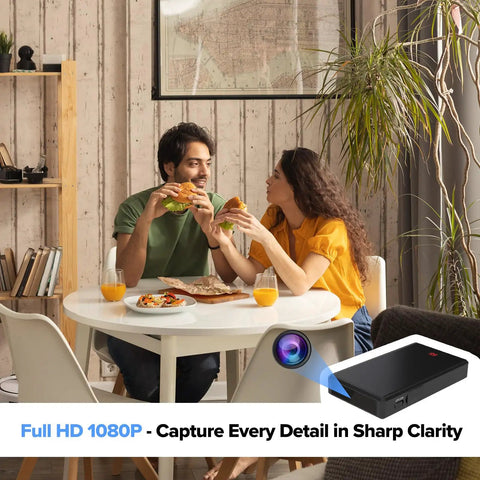 Couple eating pizza in living room with 1080p WiFi Security Cam With Night Vision Indoor Outdoor Nanny Cam For Home Or Office Local And Cloud Storage Quick Setup Sleek Minimalist Build That Blends In Anywhere visible in corner