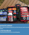 Front view of an open Amazon BISS first aid kit in red/black, 324-piece with labeled compartments.