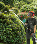 Man trimming hedges with Five In One 26cc Gas Powered Two Stroke Garden Tool Kit with Dual Sided Hedge Trimmer in garden