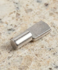 Close-up of stainless steel shelf pin, 5mm cabinet fastener for glass and wood, heavy duty load bearing support on granite surface.