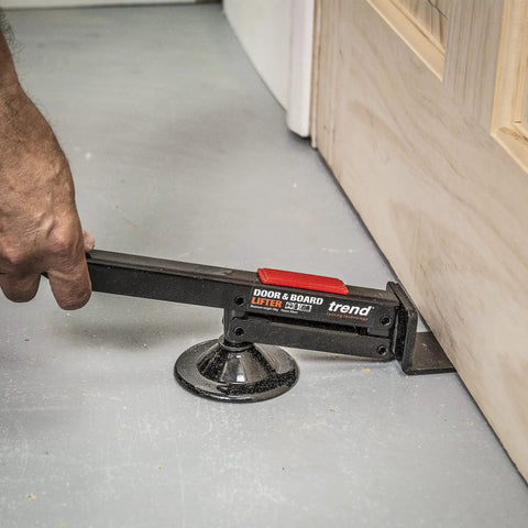 Swivel Type Door And Board Lifter With Hands Free Foot Operated Lift in use under door, showing black construction