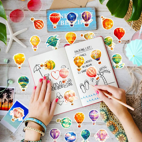 Person decorating journal with 50 Piece Hot Air Balloon Sticker Pack For Teens And Creative Vibes Waterproof Vinyl Balloons Stickers Set For Laptops Journaling Water Bottles Notebooks Classrooms And Dope DIY Decor.
