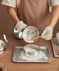 Person using Beast Power 2000W Electric Grain Mill Grinder With 750g Capacity to grind flour, shows stainless steel body and powder output.