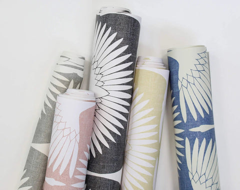 Five rolls of wallpaper featuring a feather pattern, including Genevieve Gorder Sahara Blush Feather Flock Peel and Stick Wallpaper.
