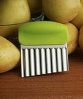 Front view of a green-handled stainless steel crinkle cutter with a wavy blade; part of a 2-piece kitchen set