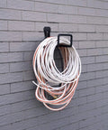 Heavy Duty Metal Hose Holder Wall Mount for Garden and Expandable Hoses installed on outdoor wall with 100 ft hose wrapped.