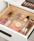 Level Up Your Vanity Game With This 10 Piece Clear Drawer Organizer Set, featuring clear bins holding cosmetics and brushes in a tidy drawer.
