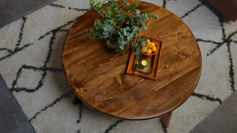 Round wooden table with a gloss finish, displaying a vase and fruit, enhanced by Triple Thick Polyurethane Clear Wood Finish.