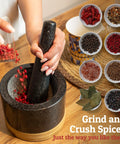 Heavy Duty 100 Percent Natural Granite Mortar And Pestle Set With Bamboo Base 2 Cup Capacity Black Stone Grinder in use with spices